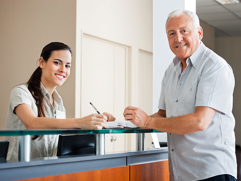 Friendly receptionist helping patient at frontdesk of Neck, Back, Arm, Leg and Headache Pain Relief Clinic of Marin in San Rafael