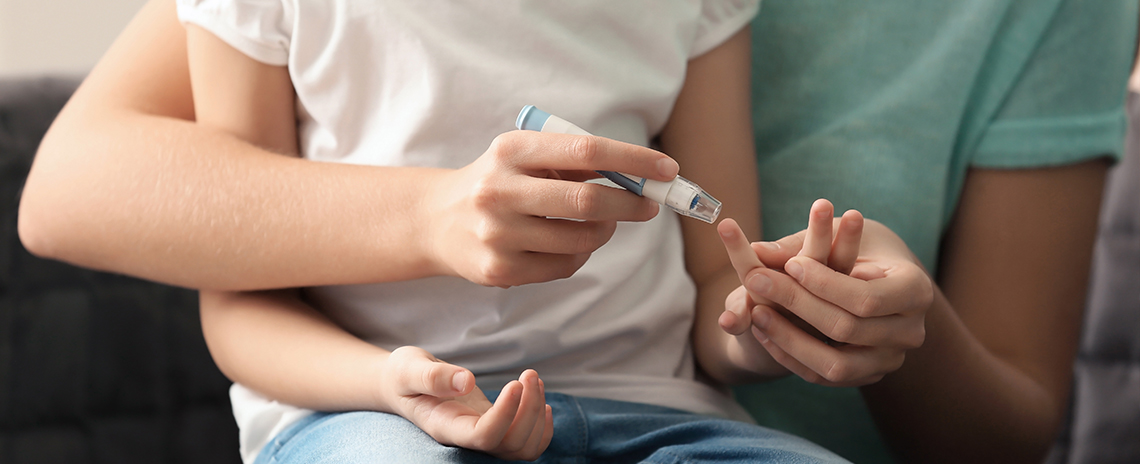 Mother holding her child and testing the child's blood suger levels with a finger prick tester