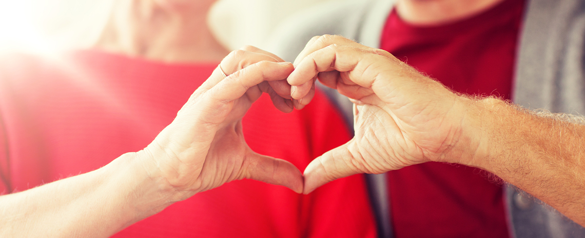 Mature couple holding hands in heart shape