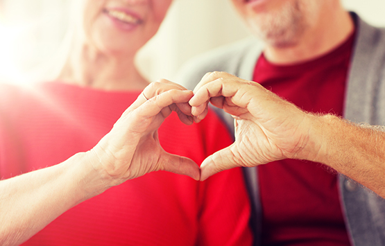 Mature couple holding hands in heart shape