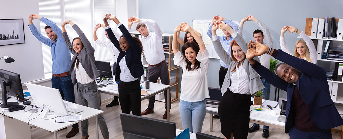 An office team stretching in office together