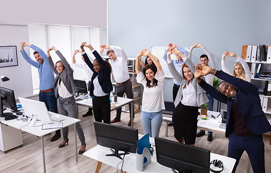 An office team stretching in office together